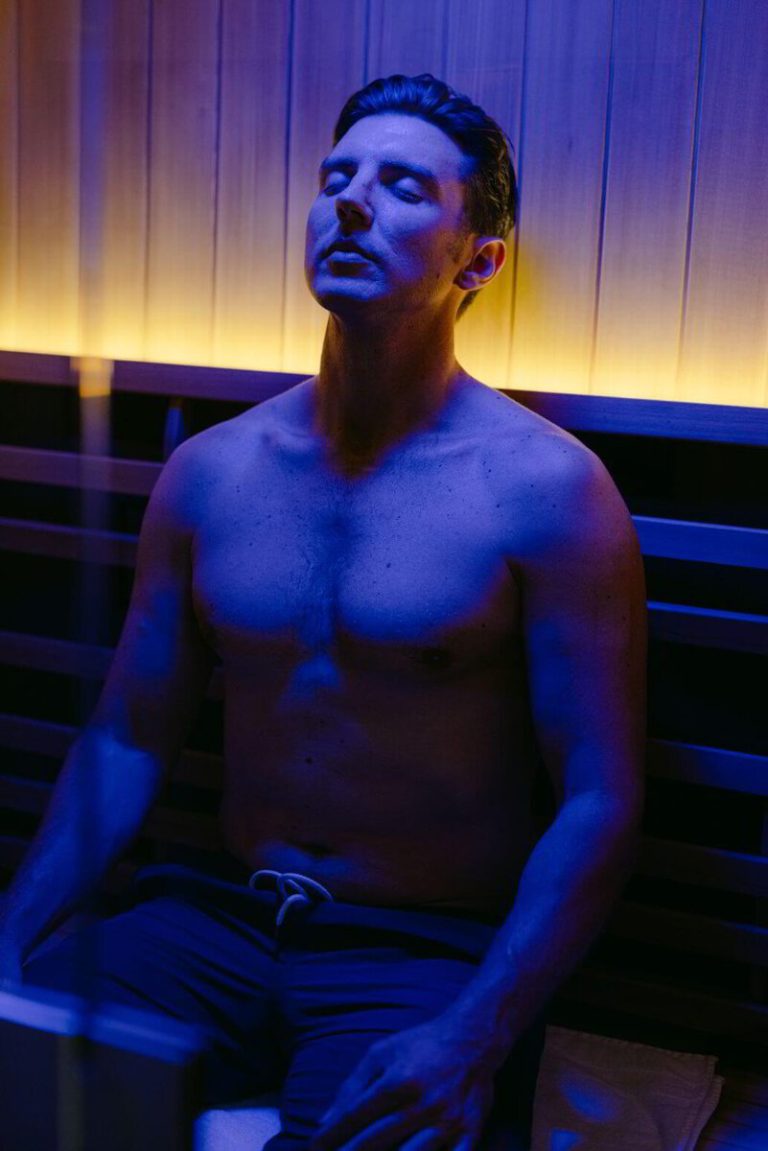 shirtless man relaxing in infrared sauna