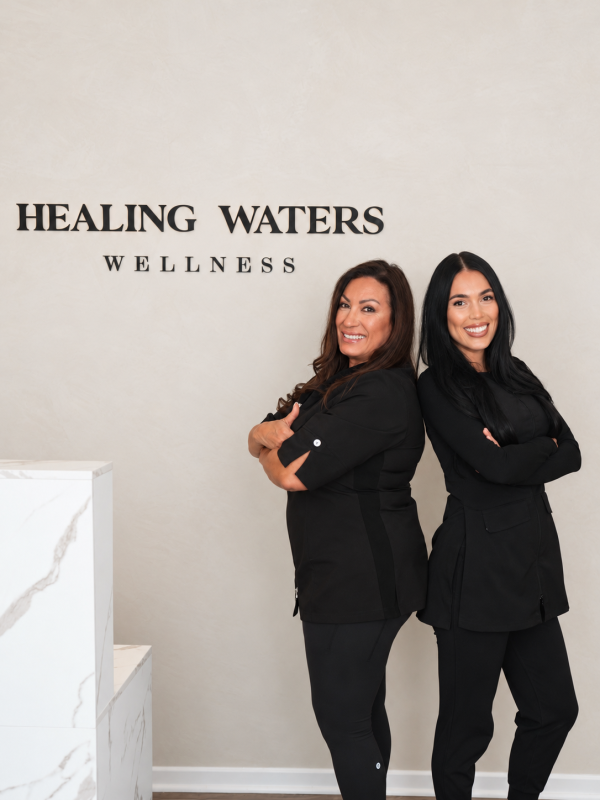Mother-and-daughter owners standing in front of the Healing Waters Wellness sign